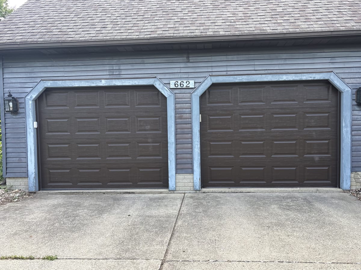 Two new brown raised-panel garage doors installed on a residential two-car garage